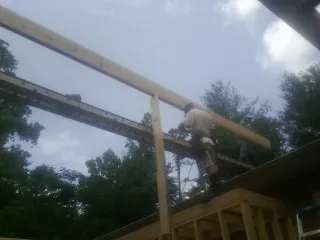 Carpenter setting a ridge beam over a new addition frame — Ice Dam Removal by Roofing Brothers in Menlo