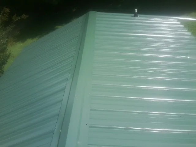 New green metal panels meeting at the ridge of a roof — Flat Roof Repair work by our crew in Menlo