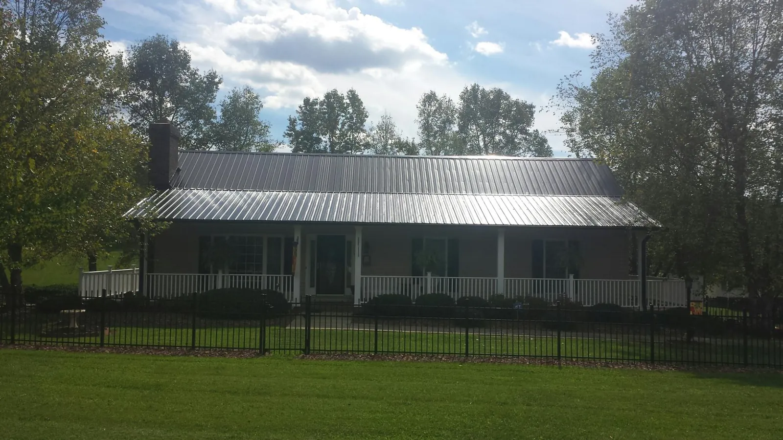 Gray metal roof on a brick ranch with a full width front porch — Gutter Guard Installation work by our crew in Menlo