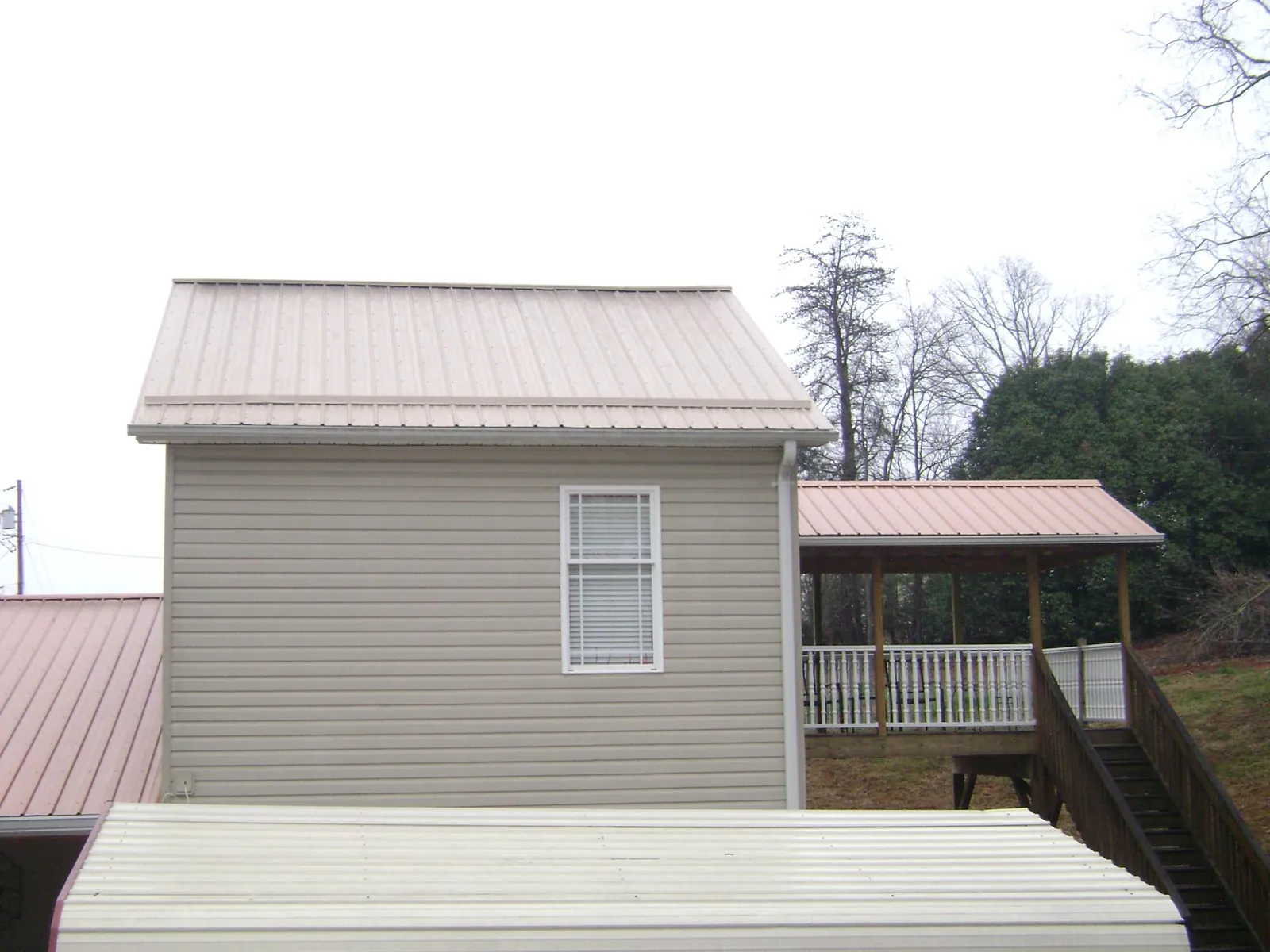 Tan metal roofs on a two story addition and attached porch, from a Roof Replacement job in Menlo