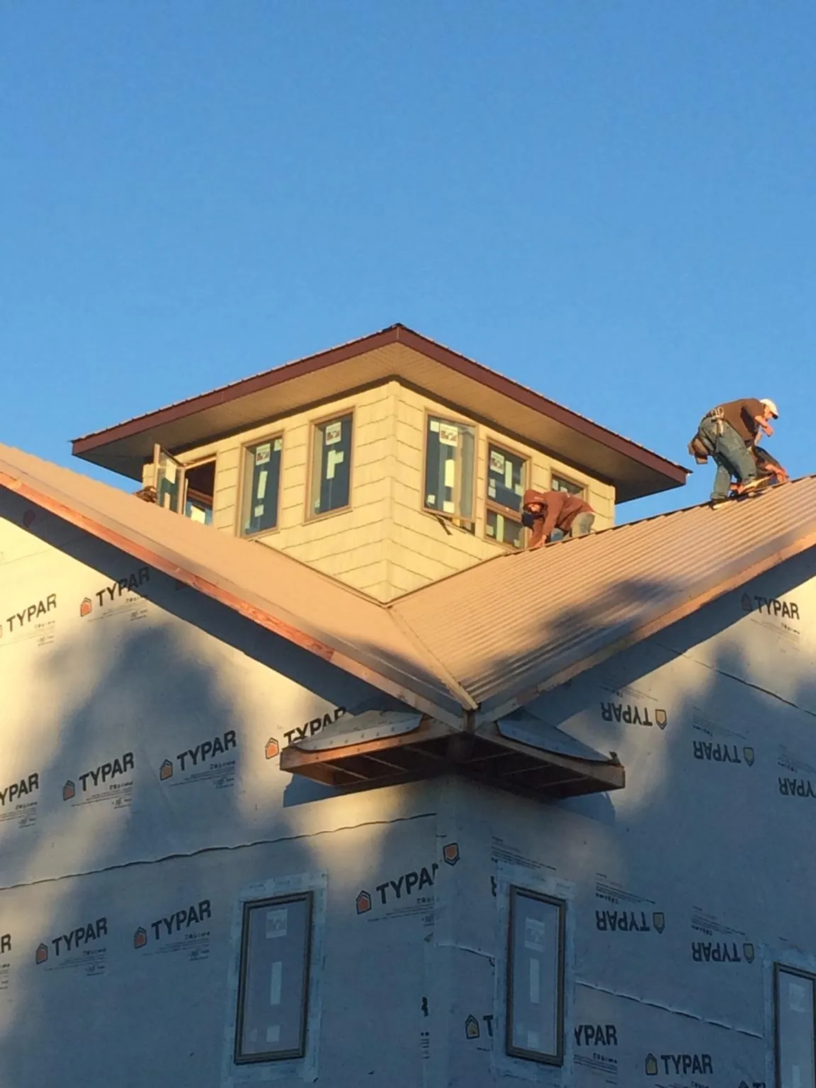 Roofers working around a rooftop cupola on a new metal roof at sunset — Roof Waterproofing in Menlo by Roofing Brothers